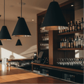 Bar counter with black and silver pendants in a dimly lit bar setting