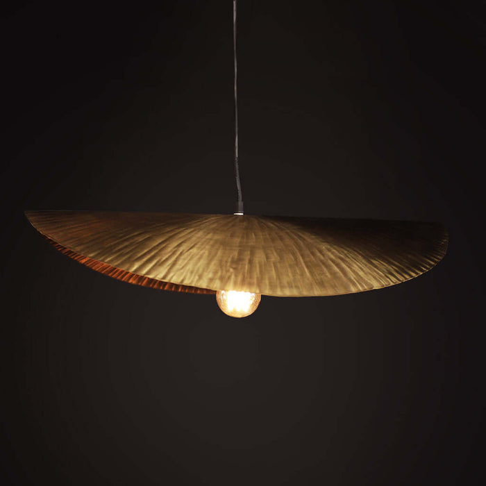 Gold pendant light with a textured shade against a black background