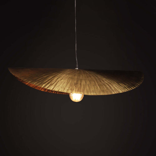 Gold pendant light with a textured shade against a black background