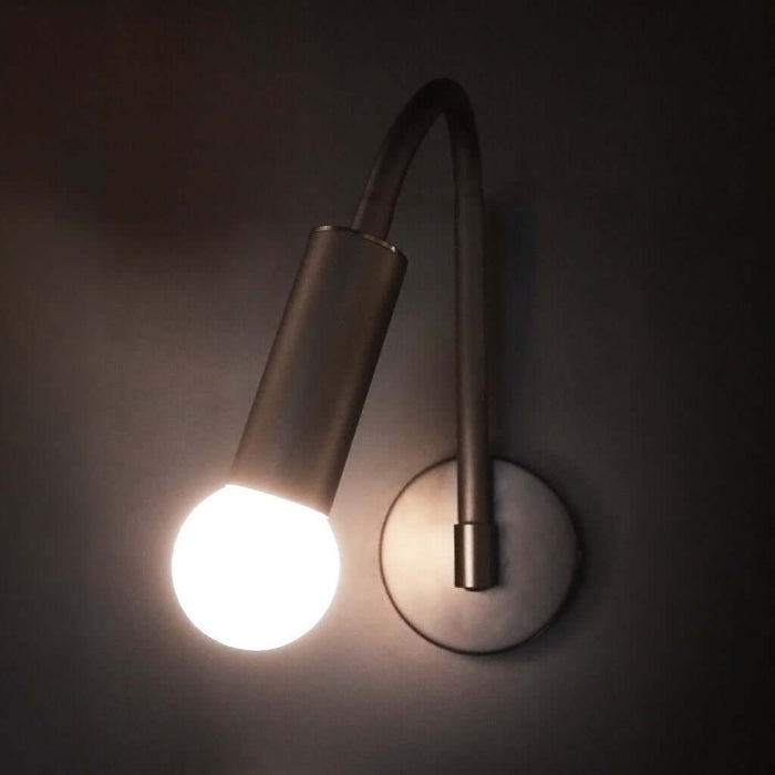 Wall-mounted lamp with tilting arm on a dark background