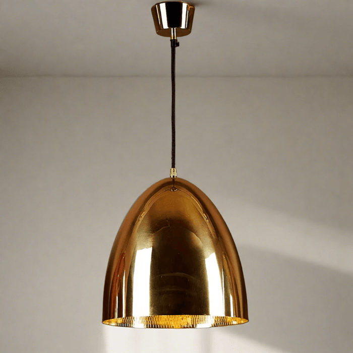 A brass pendant light with a wide brim and reflective interior, hanging from a ceiling cord.