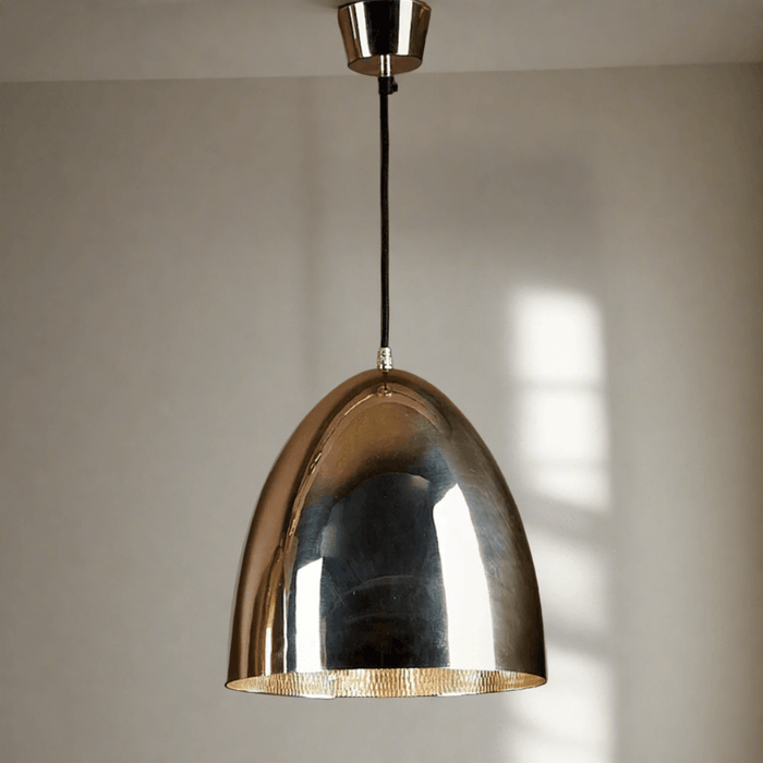 A polished nickel pendant light with a wide brim and a reflective interior, hanging from a ceiling mount via a black cord.
