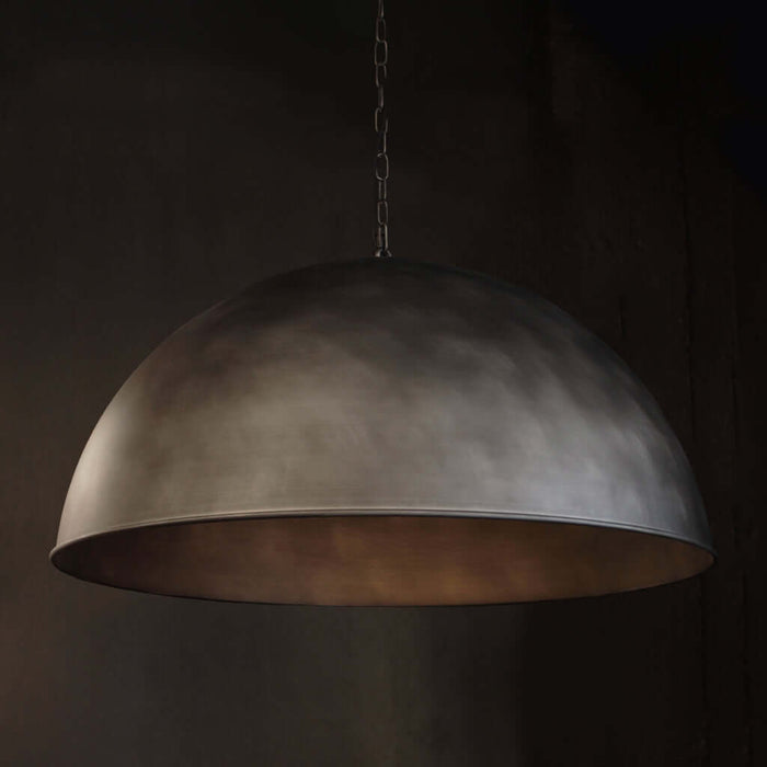 A large dome-shaped pendant light with a textured, metallic Silver finish, hanging from a chain against a dark background.