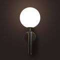 Modern wall lamp with a round white shade and black metallic base on a dark background