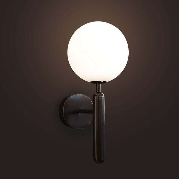 Wall-mounted light fixture with a round glass shade on a dark background