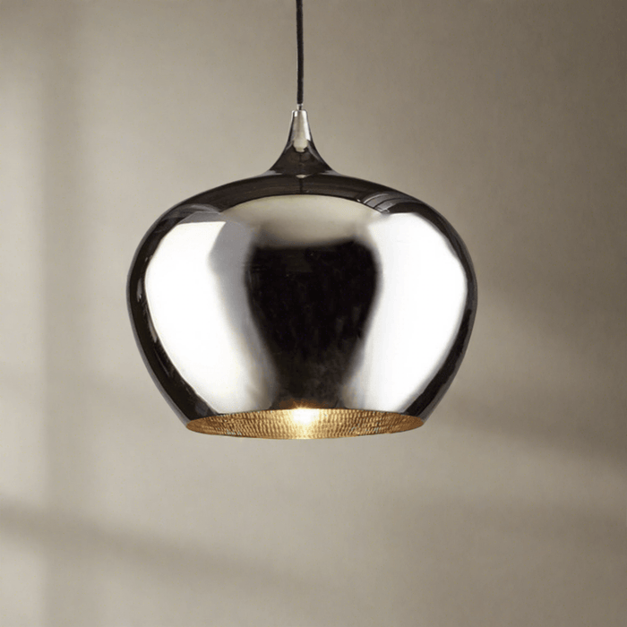 A modern teardrop-shaped pendant light with a highly reflective polished silver dome and a textured gold interior, suspended by a thin black cord against a neutral beige wall.