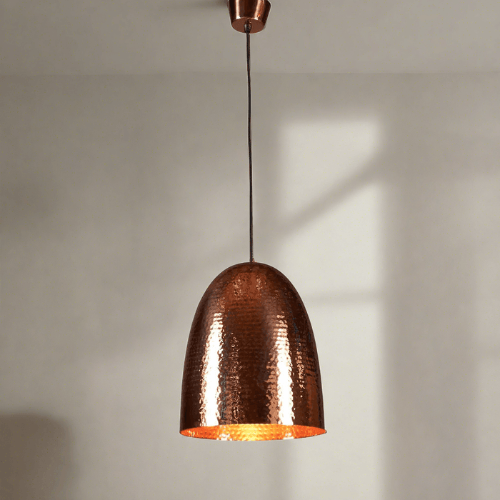 A tall domed pendant light with a hammered metal texture, constructed from a brass base, with a copper finish.