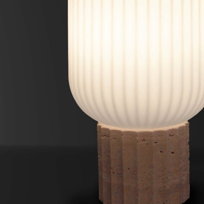 Lamp with ribbed white shade on a textured brown base against a black background