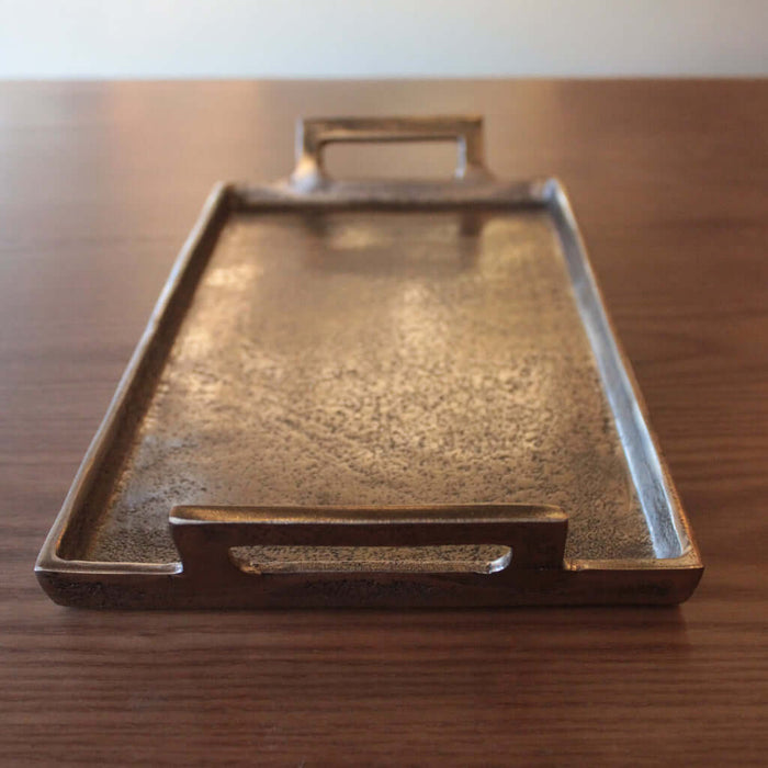 Bronze tray with handles on a wooden surface