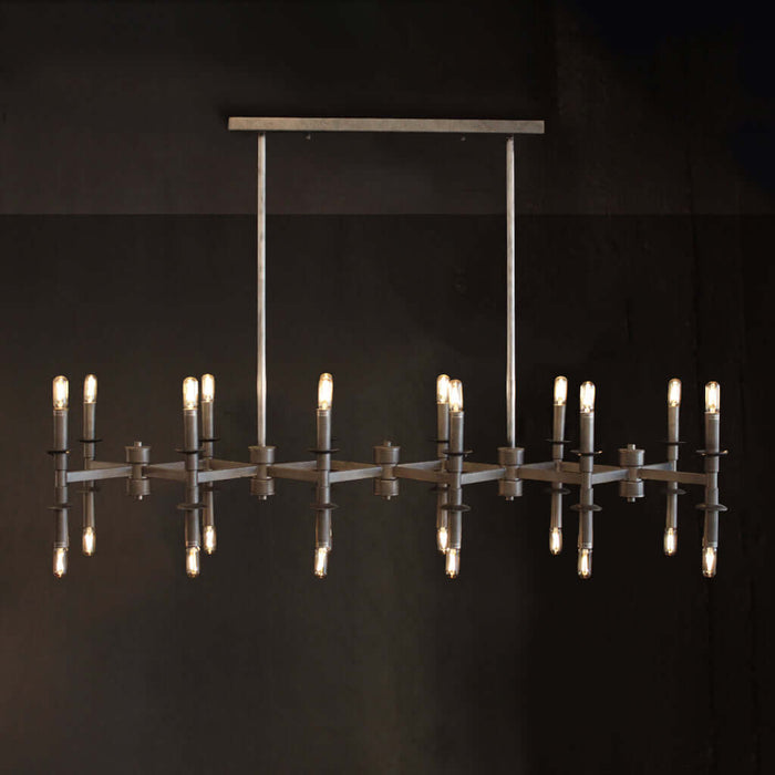 A modern industrial-style chandelier with a brushed metal frame, vertical hanging rods, and multiple candle-style bulbs, shown against a dark background with reflections below.